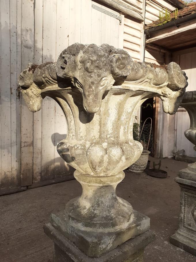 A Pair Of Rams Head Urns On Plinths