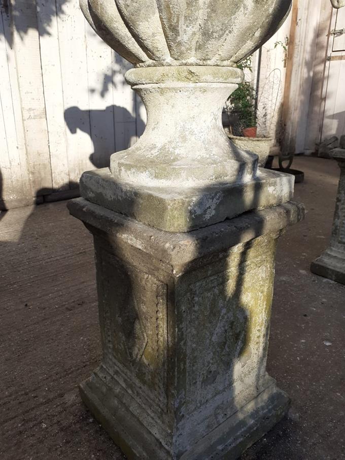 A Pair Of Rams Head Urns On Plinths