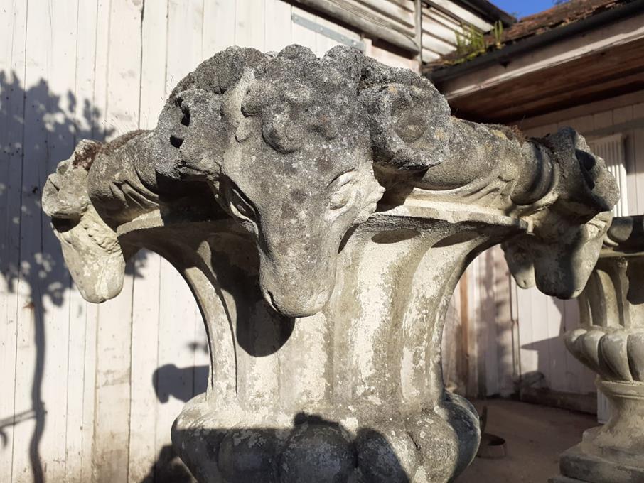 A Pair Of Rams Head Urns On Plinths